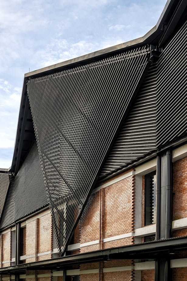 Facade detail with warm and cold surfaces - Perorated raw clay brickwork and black steelwork