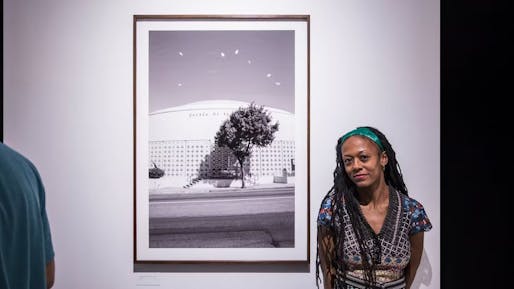 Janna Ireland photographed next to her 2017 exhibition 'There is only one Paul R. Williams: A Portrait by Janna Ireland' featured at the WUHO Gallery. Image courtesy of WUHO Gallery. 