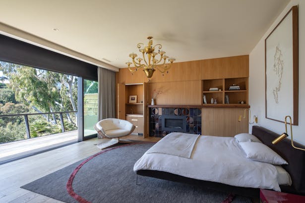 Photography by Taiyo Watanabe. In the master bedroom, with its rift oak custom wood paneled storage and vintage furnishings, fully sliding glass doors extend the room out to the deck for sweeping views of the canyon and ocean.