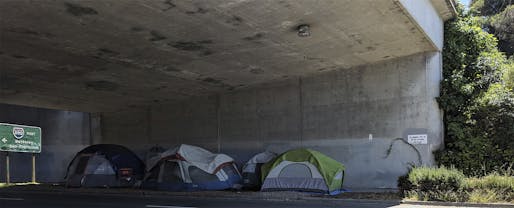 A small encampment under a freeway overpass in Oakland, California. Image courtesy Wikimedia Commons user Grendelkhan.