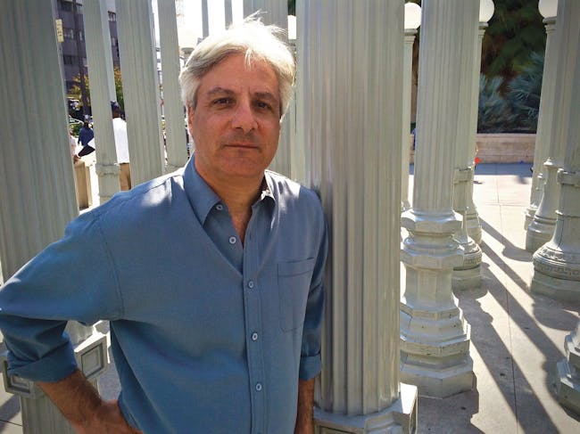 Author David Ulin standing in Chris Burden's 'Urban Light' installation, in front of the Los Angeles County Museum of Art (photo via VQRonline).