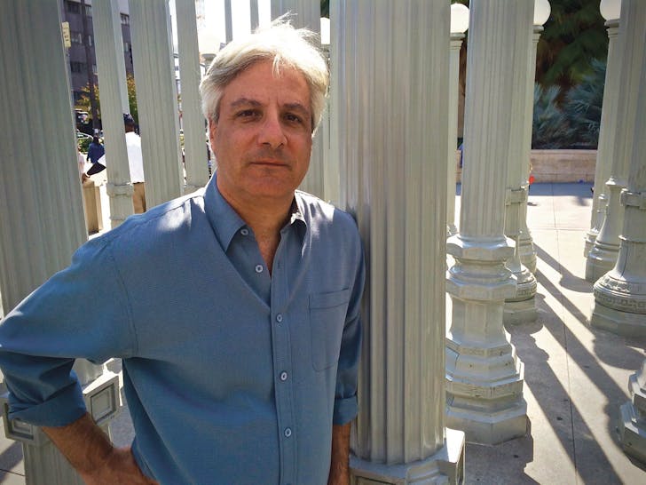 Author David Ulin standing in Chris Burden's 'Urban Light' installation, in front of the Los Angeles County Museum of Art (photo via VQRonline).
