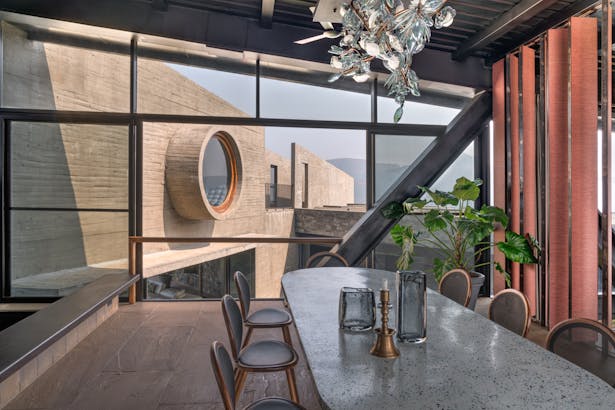 The dining room showcases a 10-foot long terrazzo table, infused with recycled glass bits which was cast entirely on site. The pivoting fins connect the user to the lower level of the house. 