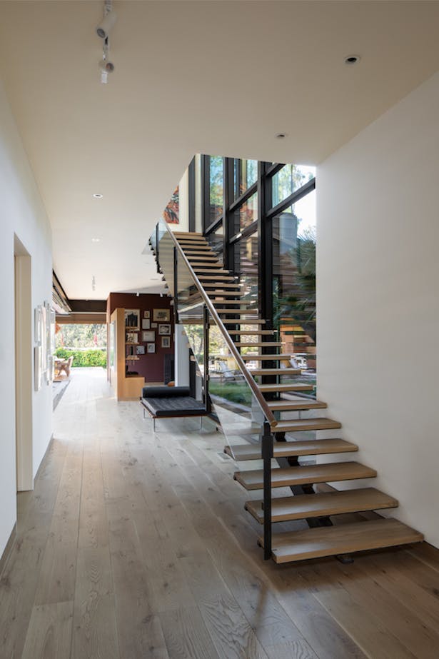 Photography by Taiyo Watanabe. In the home’s generous entryway, glass and steel support the floating french oak stairway.