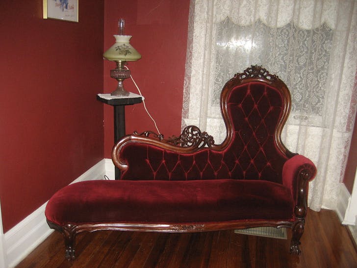 A typical fainting couch, with the one signature raised end and singular armrest. 