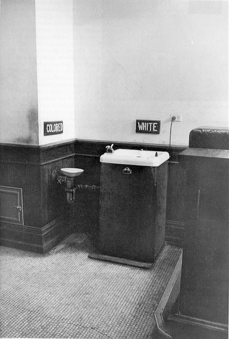 Spatial Segregation: Jim Crow Era public water fountain in the American South. This photograph tangibly depicts racialized space and discriminatory policy via the segregated drinking fountains juxtaposed against one another as differentiated amenities. Image courtesy of Todd Brown