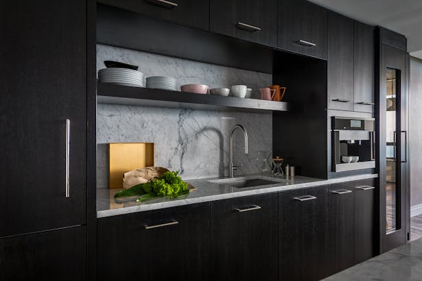 A simple stone back splash provides a dramatic contrast from the black mill work throughout the kitchen.