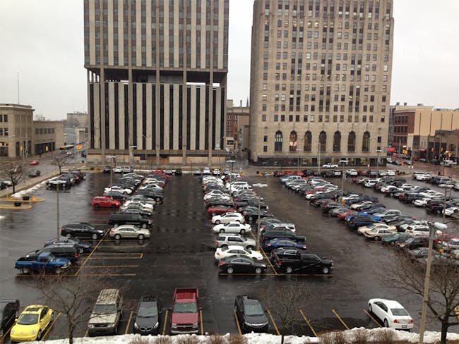 Current situation of Flint's central downtown parking lot: Mott Foundation building is on the right; Genesee Towers, on the left, is slated for demolition (Image courtesy of Flat Lot Competition)