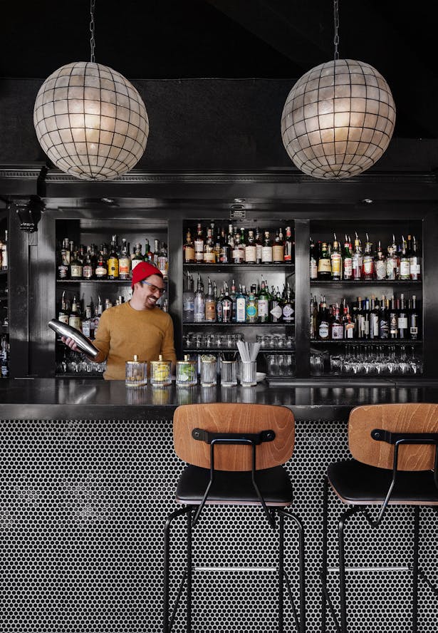 The existing bar and casework was re-imagined with shiny black lacquer, beautiful quartz bartop and penny round tiles below. New lighting and furniture lend the space a moody ambiance.
