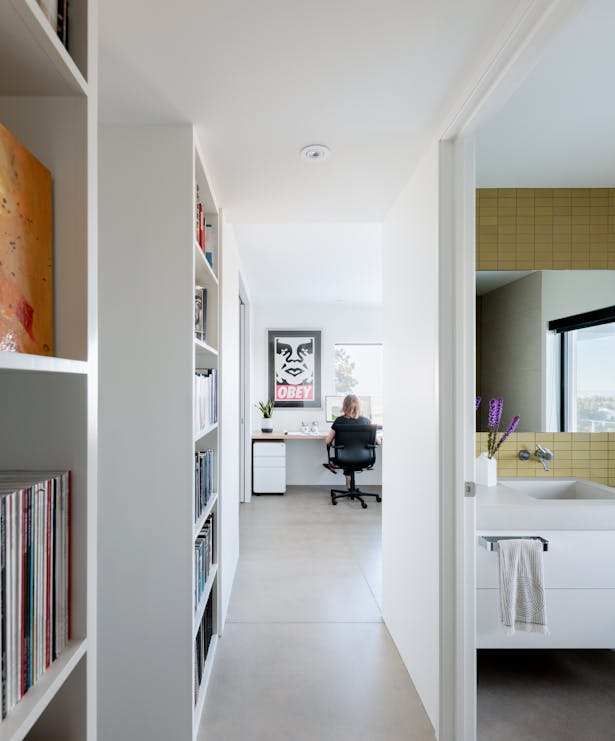 The efficient lower level space includes built-in bookcases, fun pops of color with tile, economical u-shaped built-in desk, and art centered at the end of the hallway.