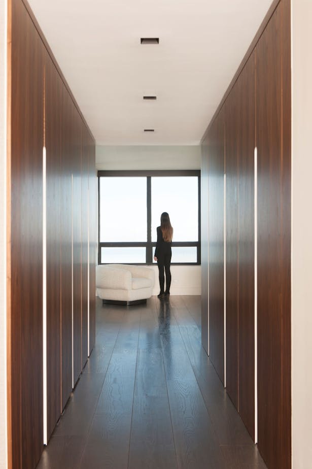 Fixed wall panels mirror the coat closets in the hall leading from a formal entry toward the living area.