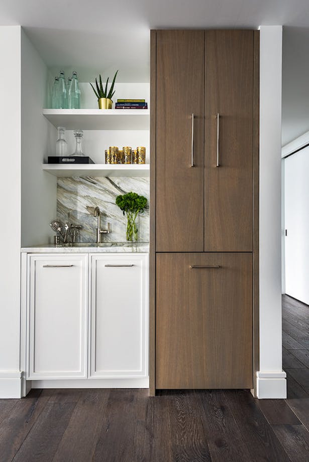 A wet bar was included with a hidden fridge in the living space. As an extension of the open kitchen concept, this provides a unique space in the condo to elevate the ability to host and socialize with guests.