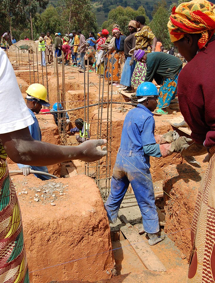 Community members pour concrete for foundations. (Photo courtesy of MASS Design Group)