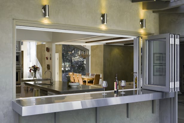 The kitchen was opened up to the rear garden through a stainless steel counter top that extends through the wall to an outside dining counter with a bifold window.