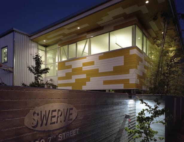 Night view from 7th Street; recycled plastic siding on new addition in yellow and white.